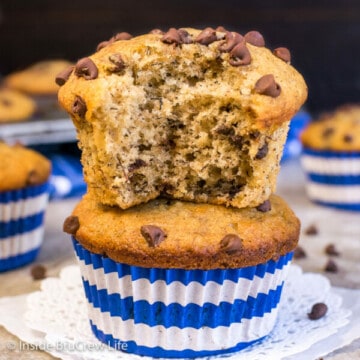 Two peanut butter chocolate chip banana muffins on a white doily with a bite taken out of the top muffin