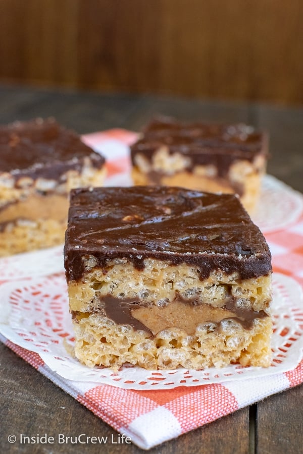 Three peanut butter cup rice krispie treats with chocolate topping laying on a towel