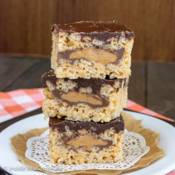 A white plate with three peanut butter rice krispies stuffed with peanut butter cups stacked on it