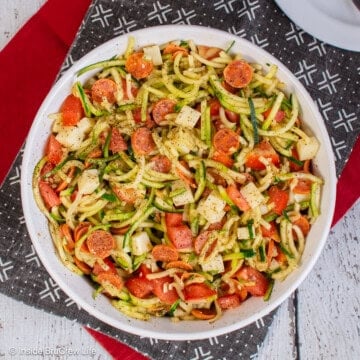 An overhead picture of a large bowl of zucchini noodle salad with pizza toppings.