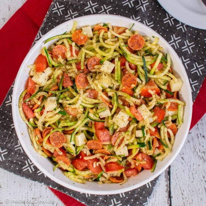 An overhead picture of a large bowl of zucchini noodle salad with pizza toppings.