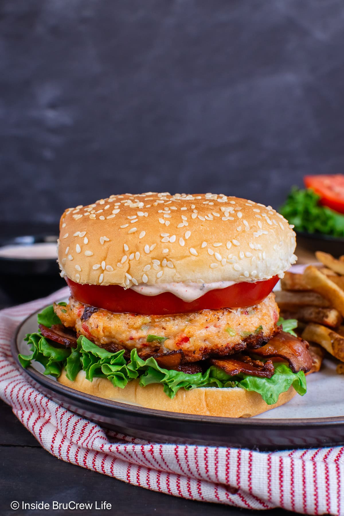 A shrimp burger on a bun with lettuce and tomato.