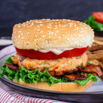 Seafood burgers on a bun with lettuce and tomatoes.