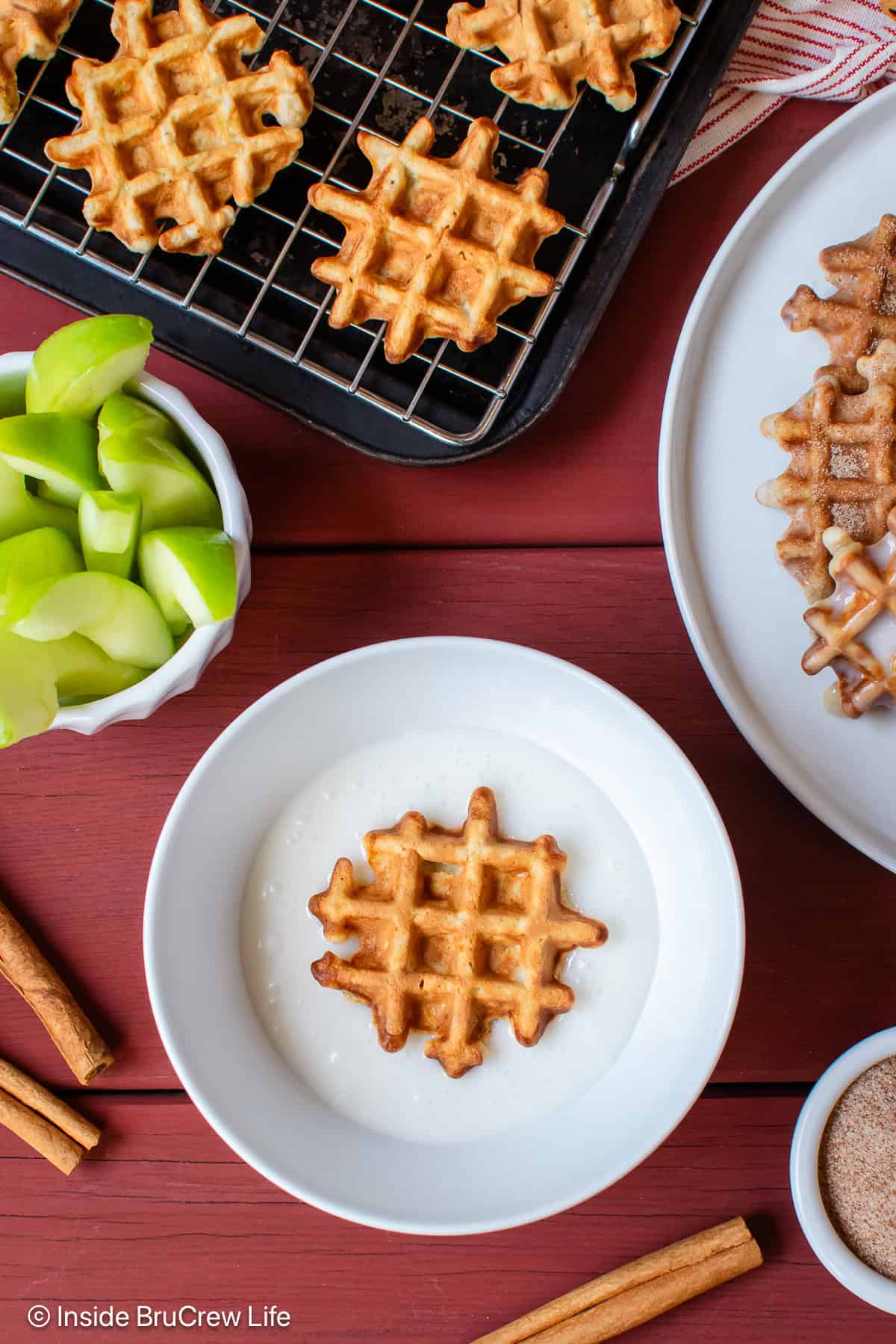 Waffle donuts being dipped into a sweet glaze.