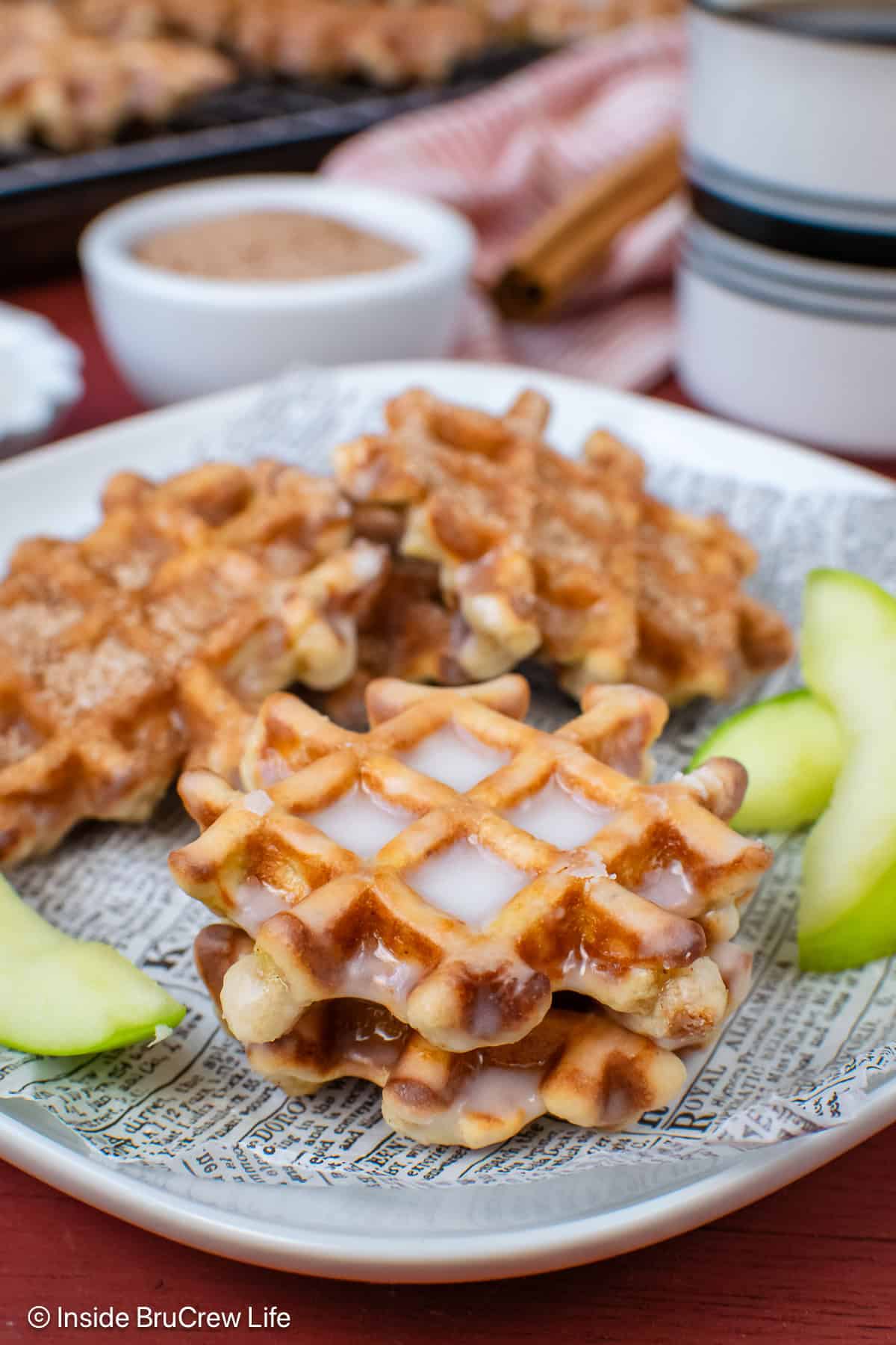 Apple waffle donuts with glaze stacked on a plate.