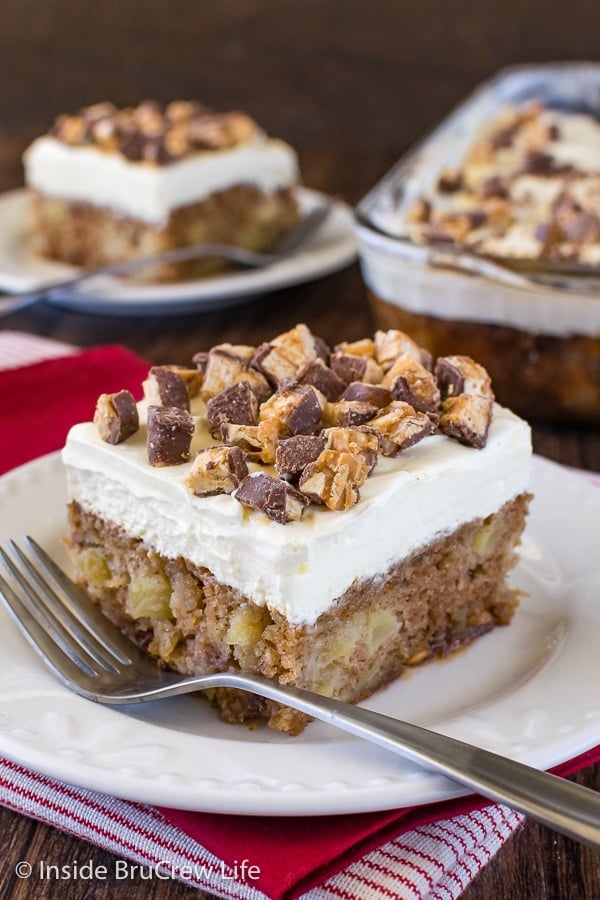 A white plate with a piece of apple Snickers cake on it and a fork beside it