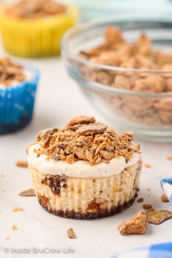 A white board with mini cheesecakes topped with Butterfingers on it.