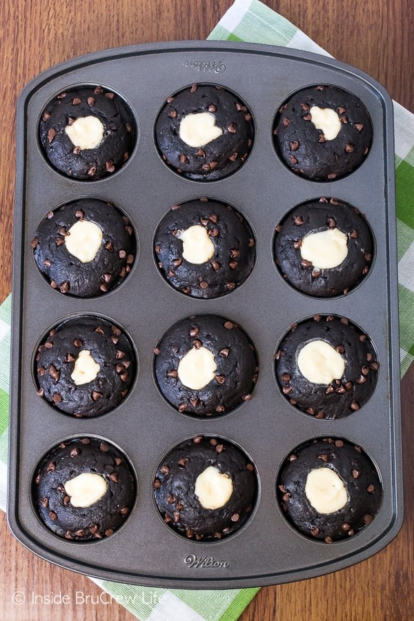 Overhead picture of a muffin tin with chocolate zucchini cheesecake muffins in it