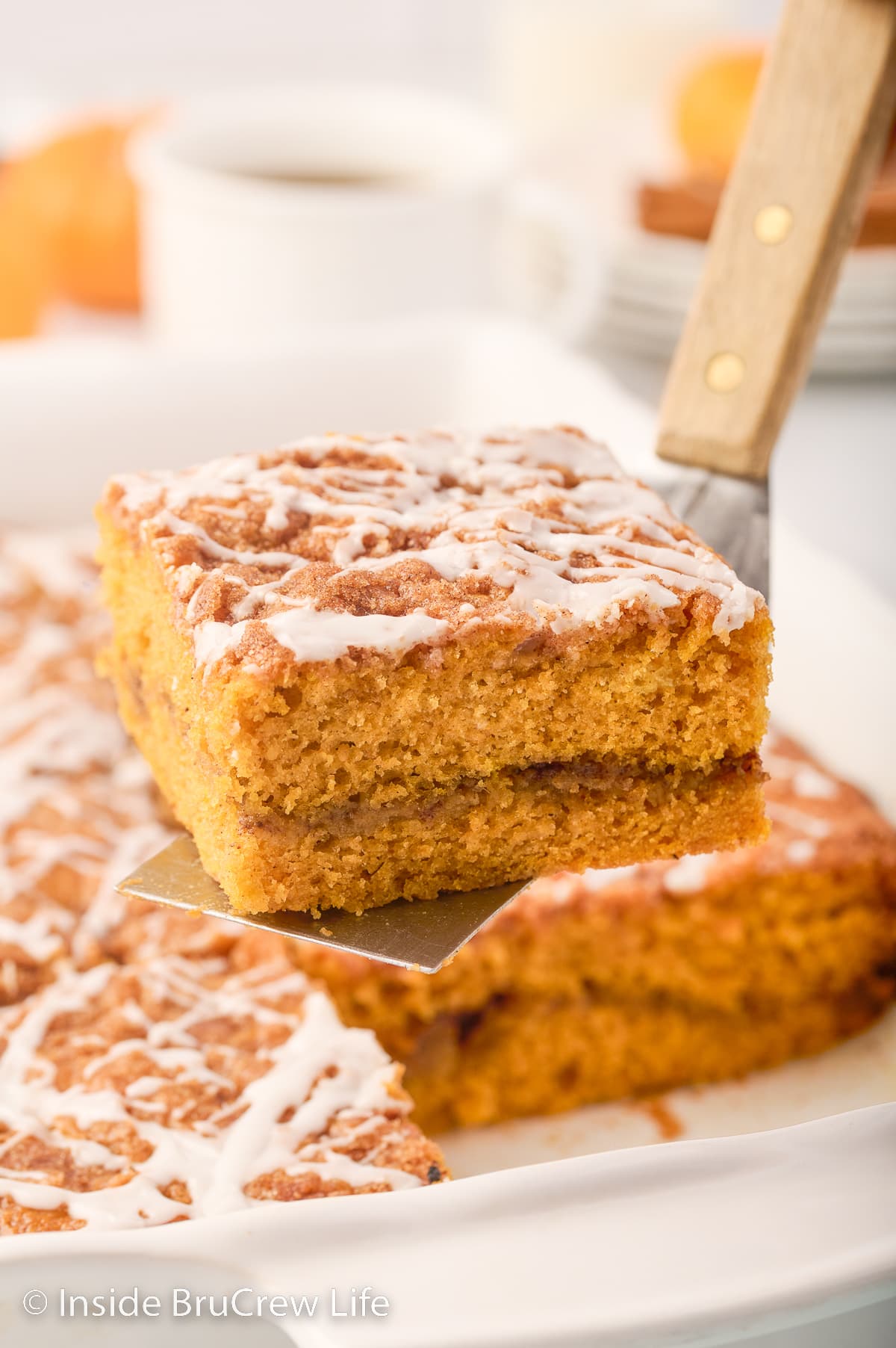 A spatula lifting a slice of pumpkin cake out of a pan.