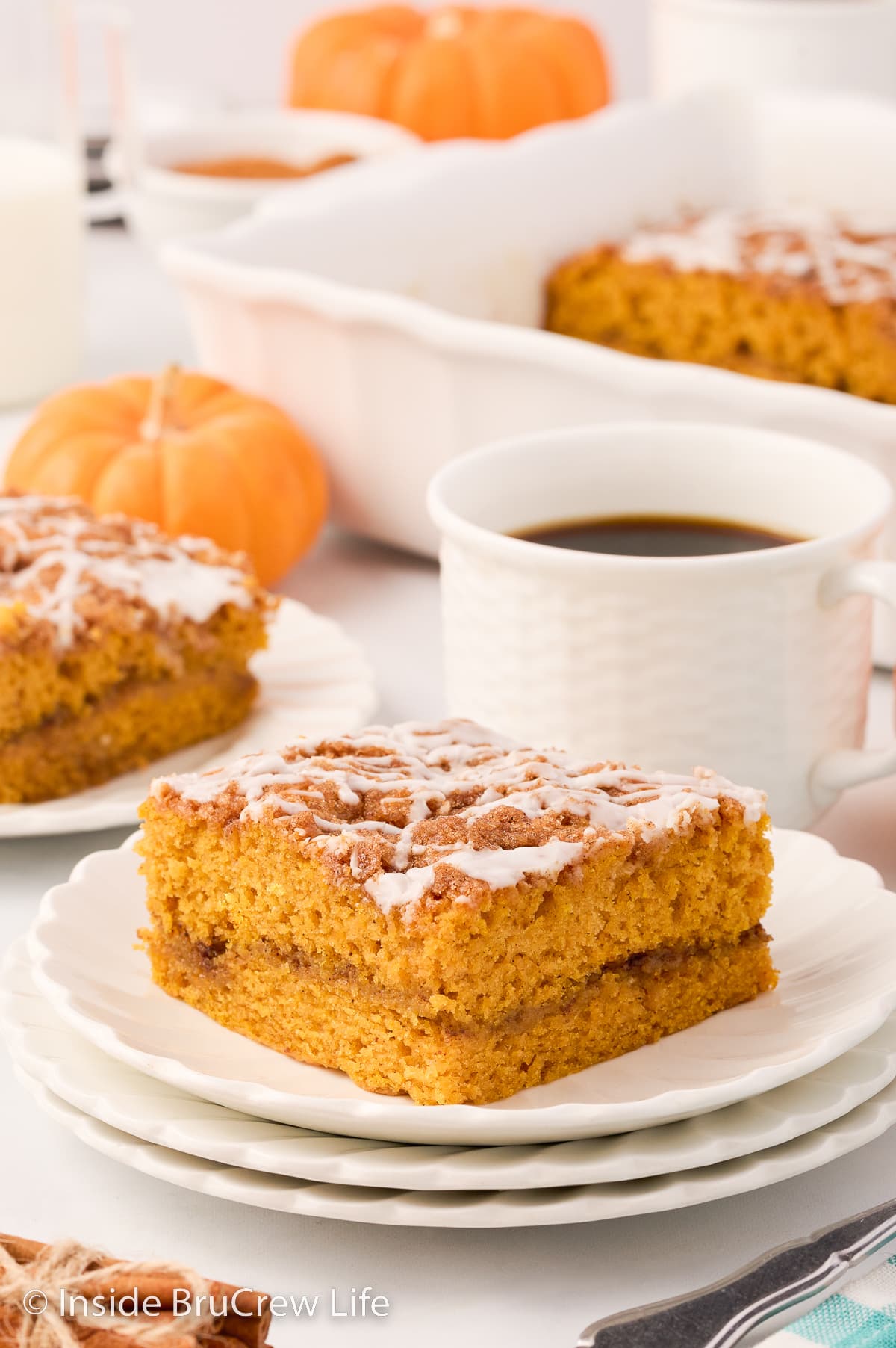 Two white plates with pieces of glazed pumpkin cake on them.