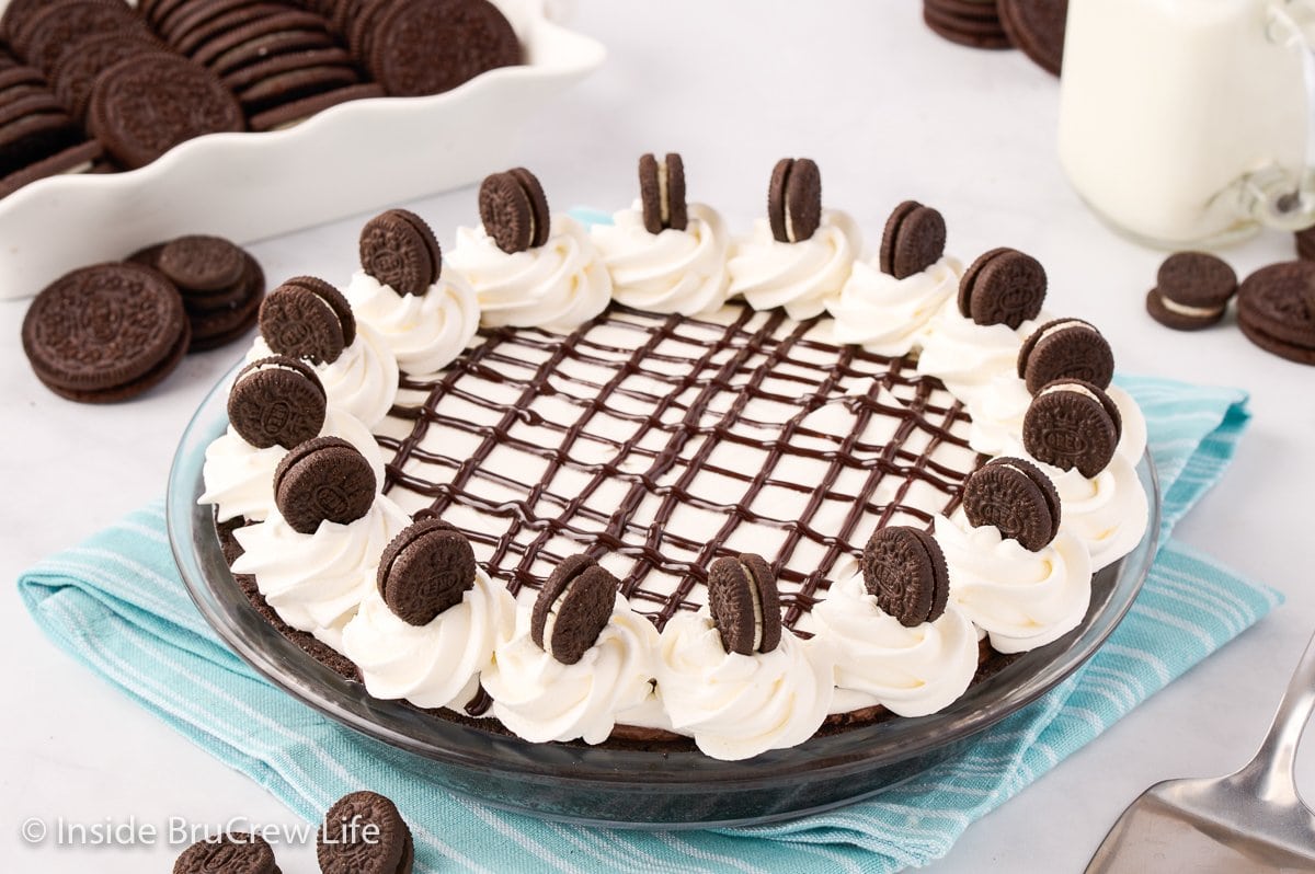 A full Oreo pie topped with whipped cream, fudge, and cookies.