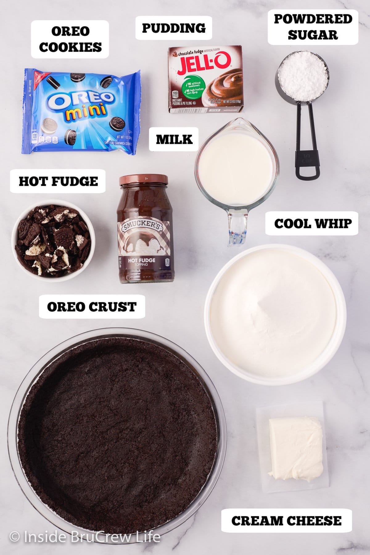 Bowls of ingredients needed to make an oreo pie on a white board.