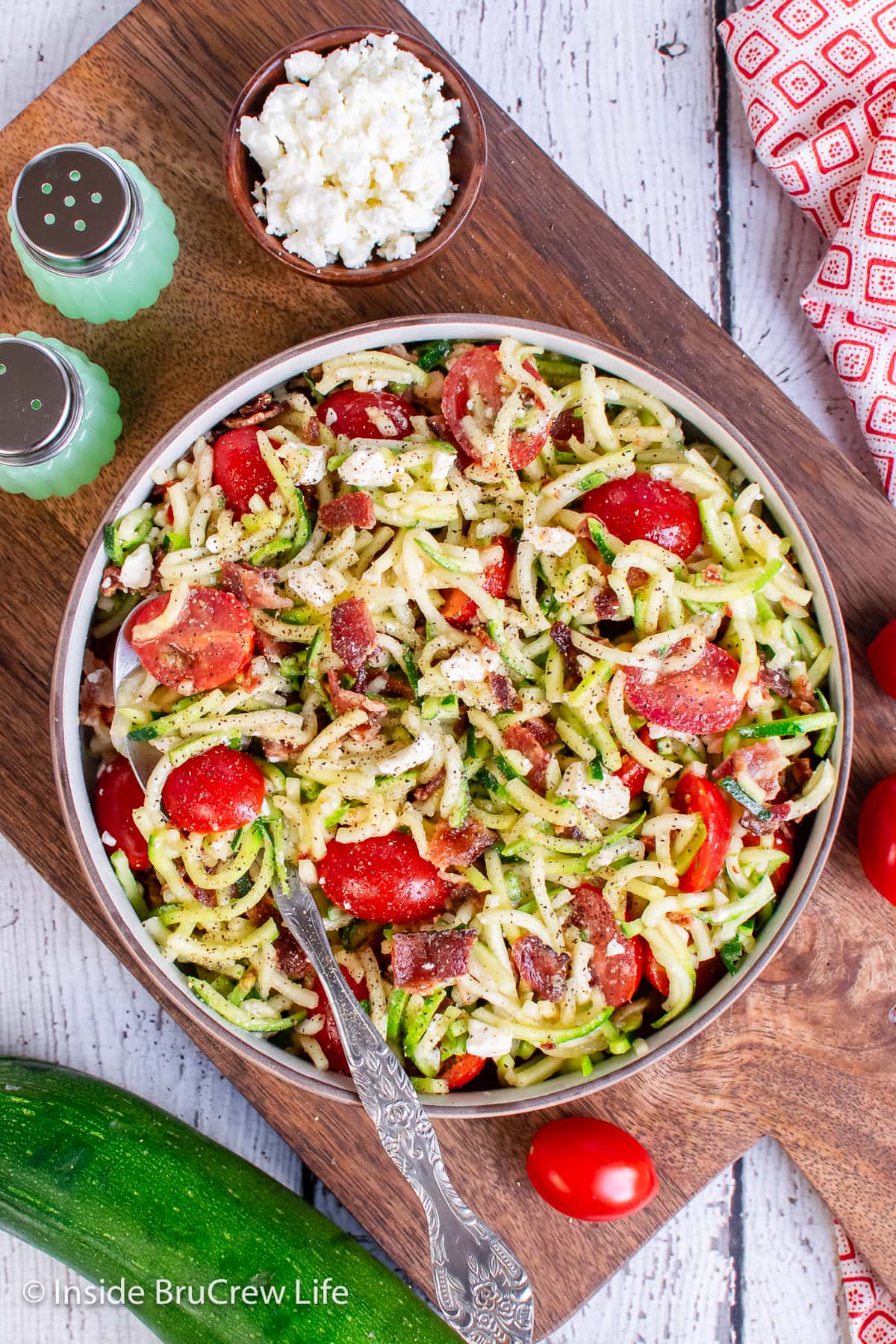 Overhead picture of a bowl filled with zoodles, tomatoes, and bacon.