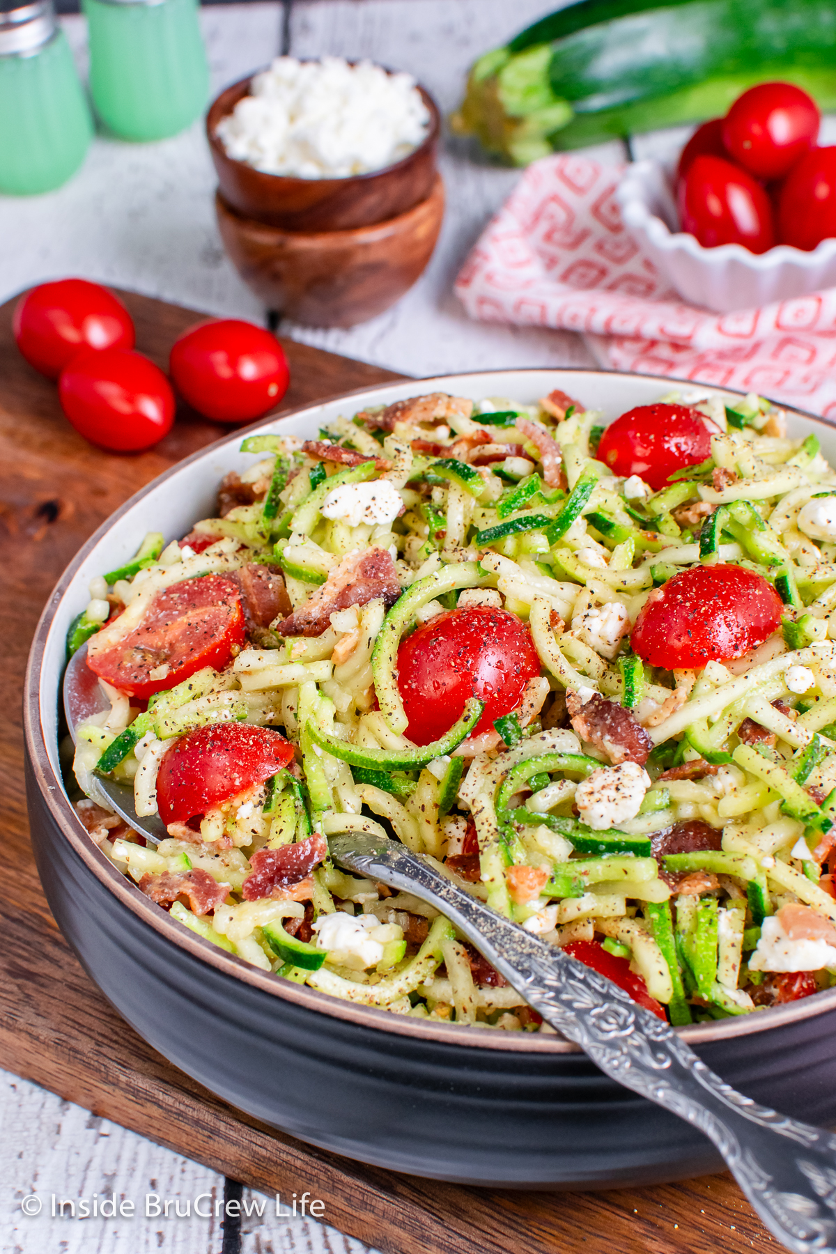 A large bowl of zucchini salad with tomatoes and feta.