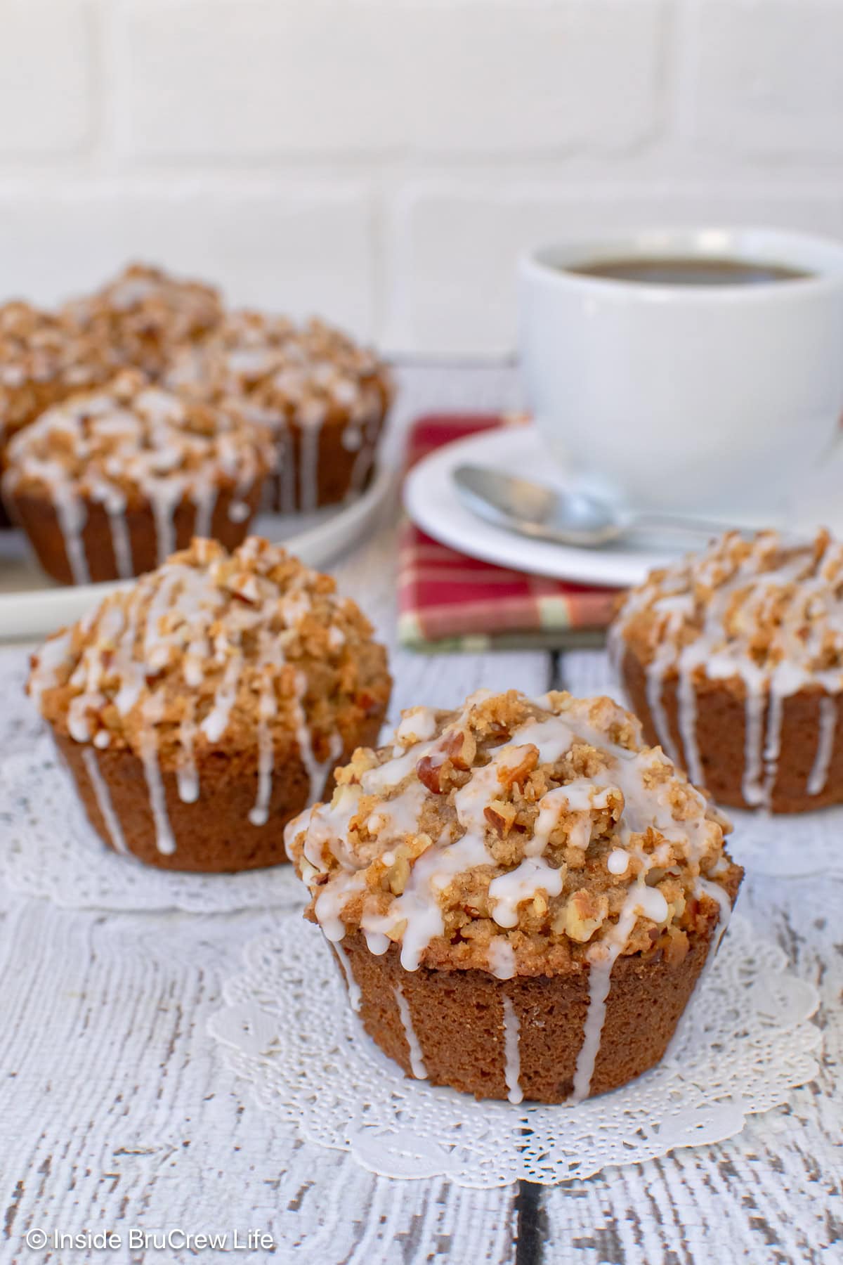 Apple muffins topped with a pecan streusel on a white board.