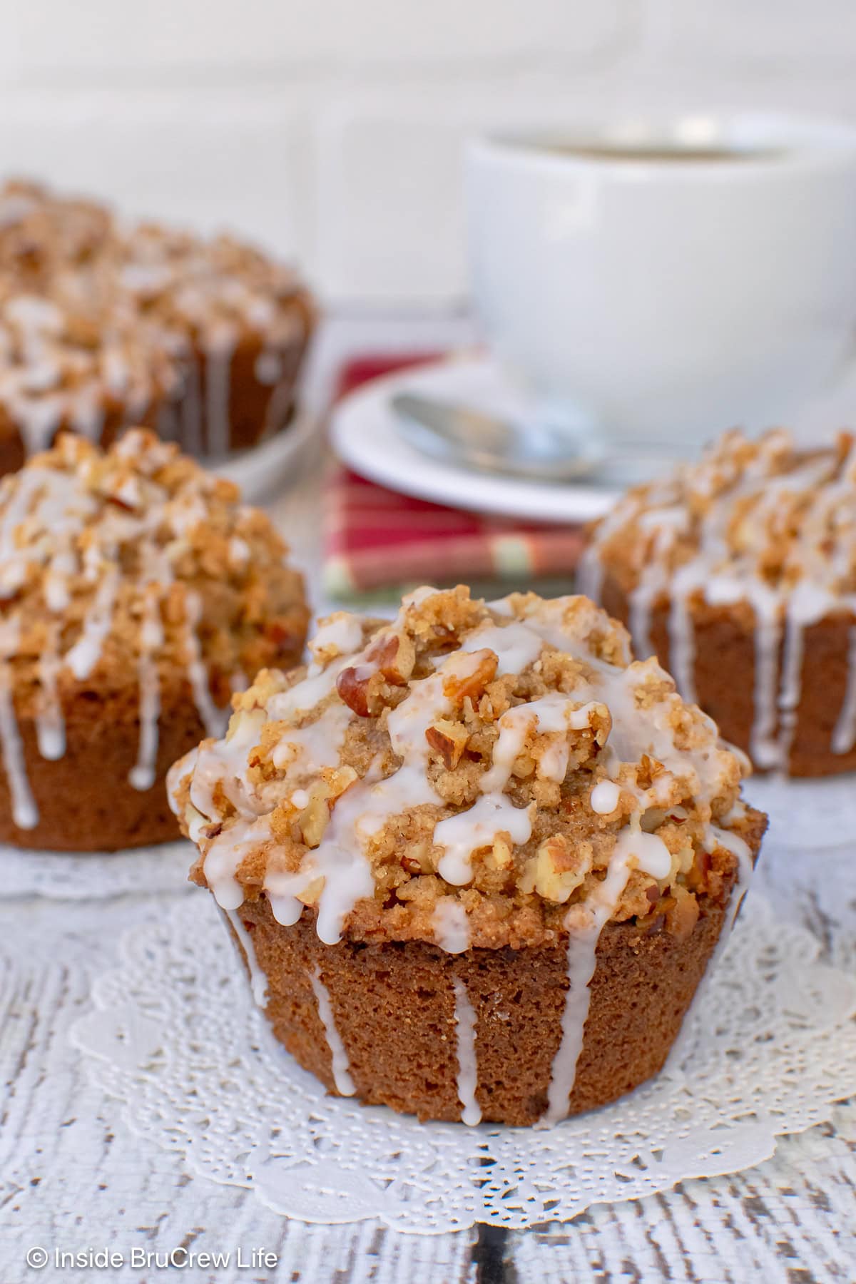 A close up of a streusel topped apple pecan muffin with more behind it.