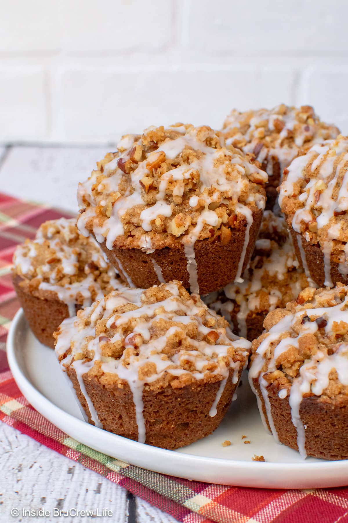 A white plate with apple pecan streusel muffins stacked on it.