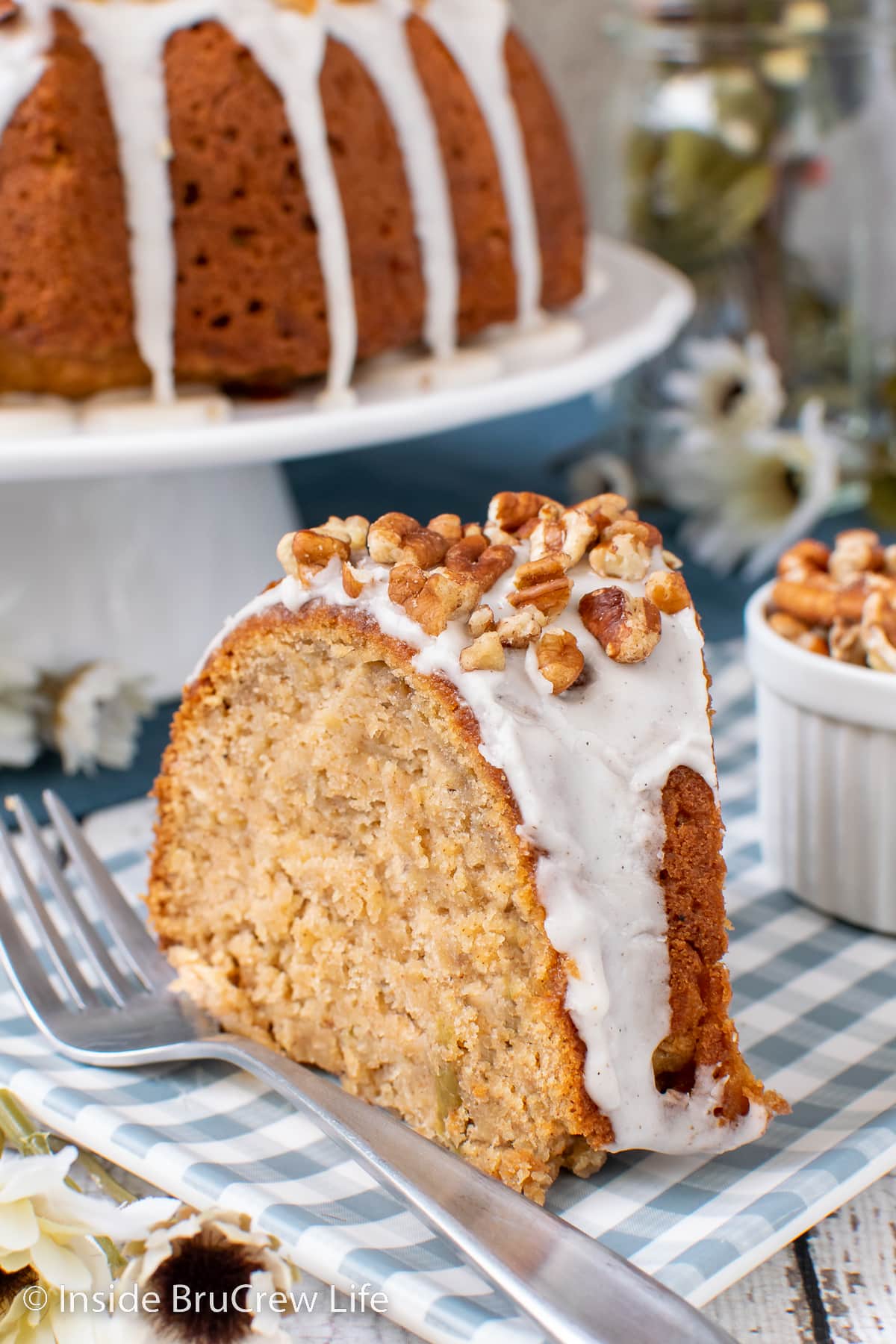 A slice of cake topped with glaze and nuts on a plate.