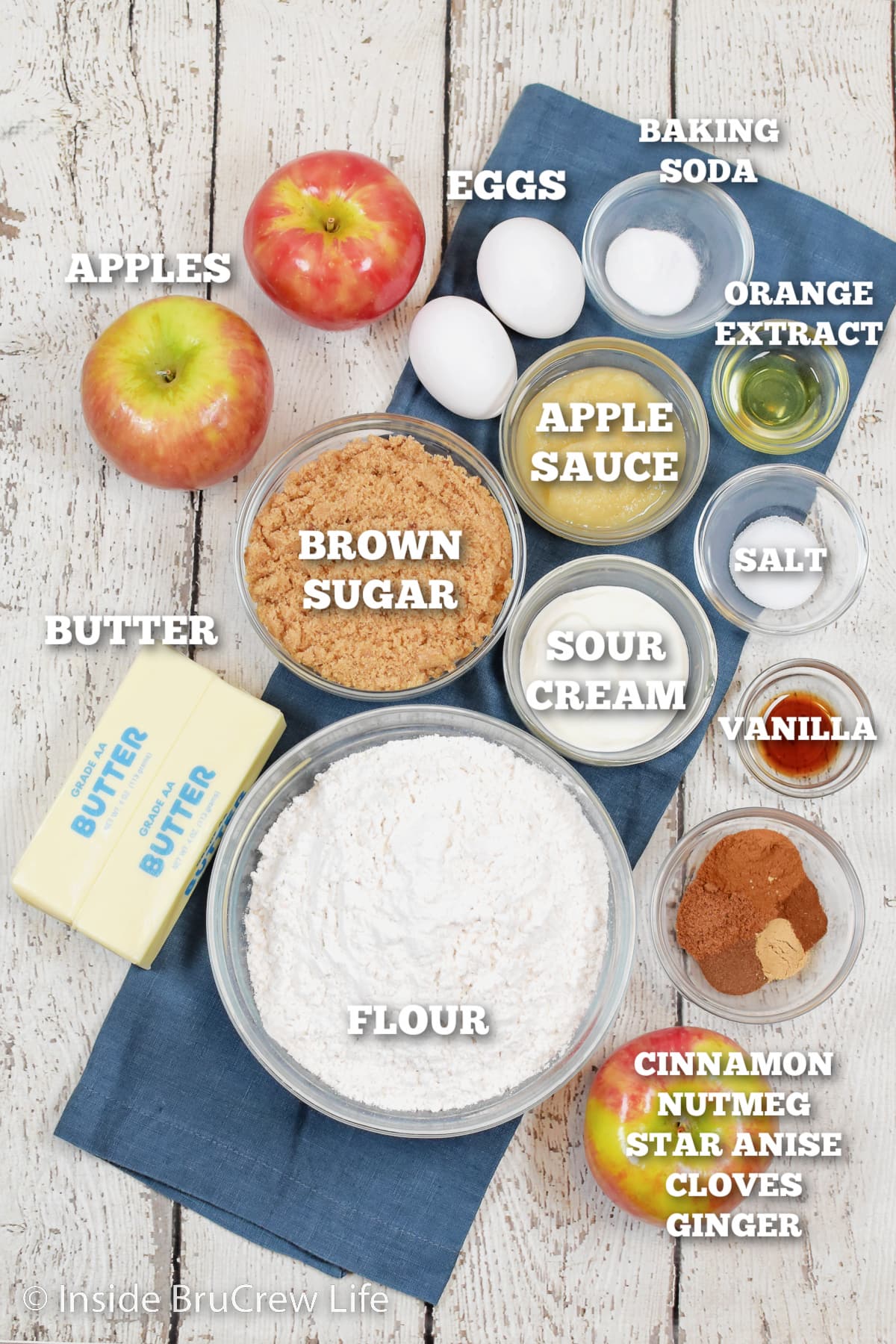 A white board with bowls of ingredients needed to make an apple cake.