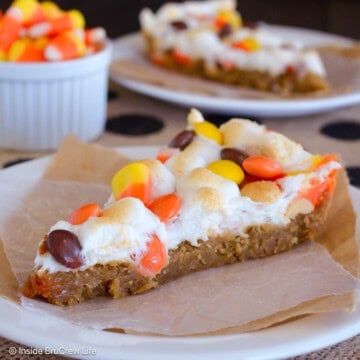 Two slices of peanut butter candy corn cookie pizza on plates.