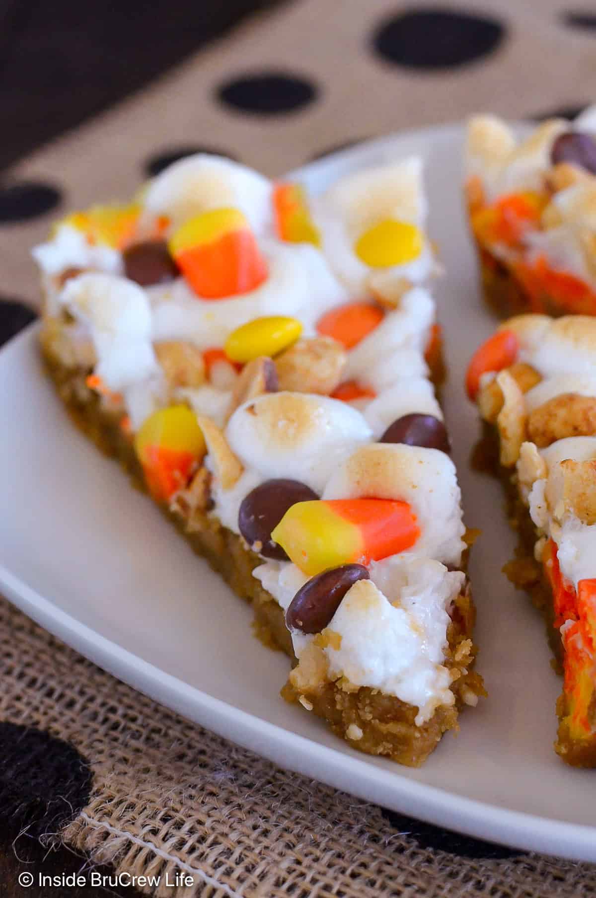 A slice of candy corn cookie pizza on a white plate.