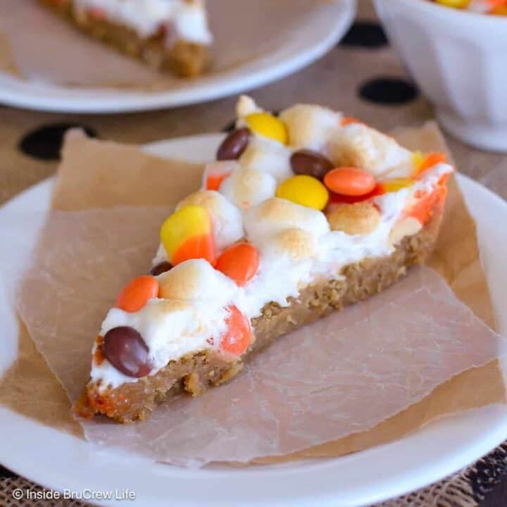 A slice of candy corn cookie pizza on a white plate.