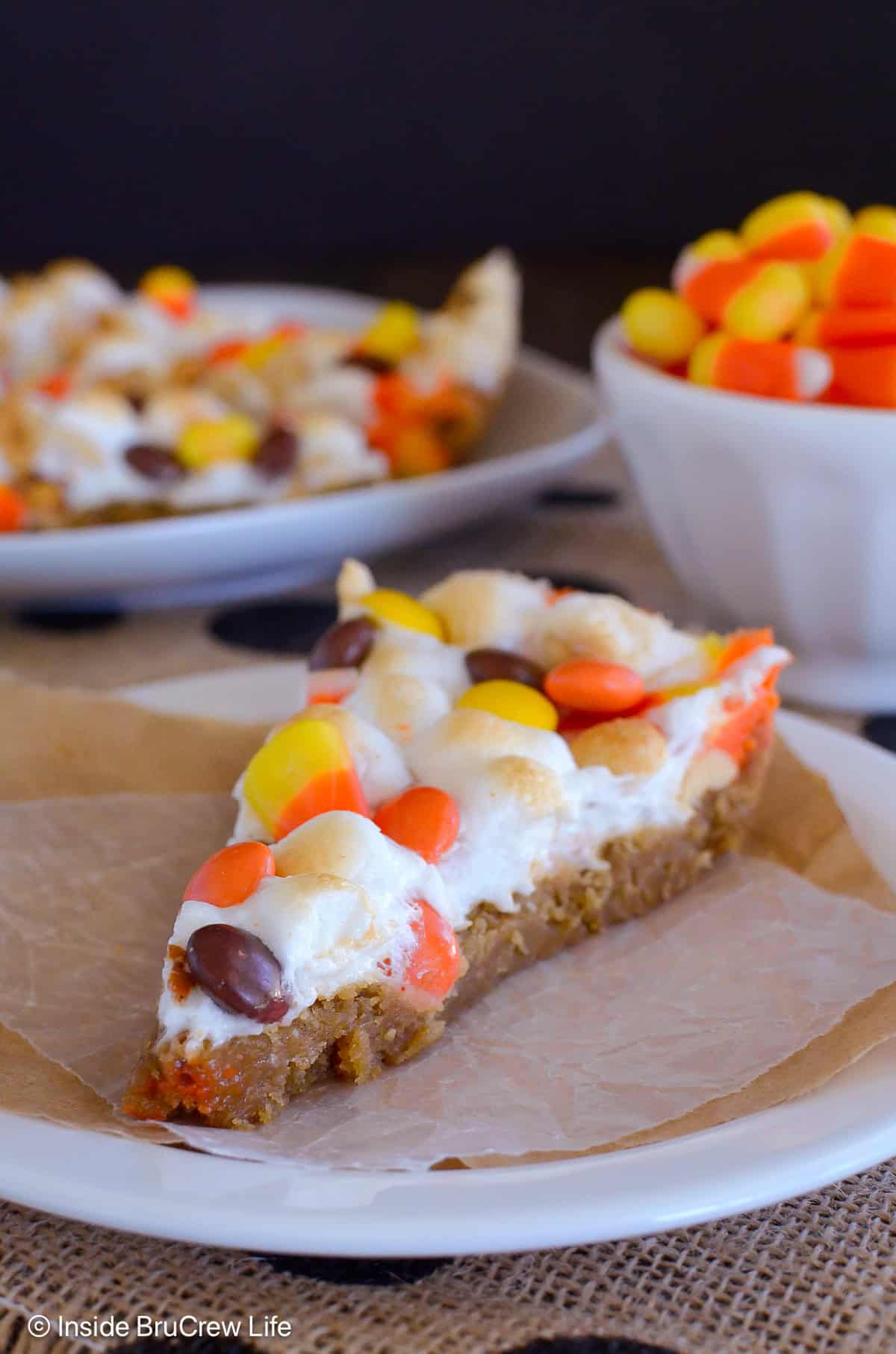 A slice of peanut butter cookie pizza with candy corn, Reese's Pieces, and melted marshmallows.