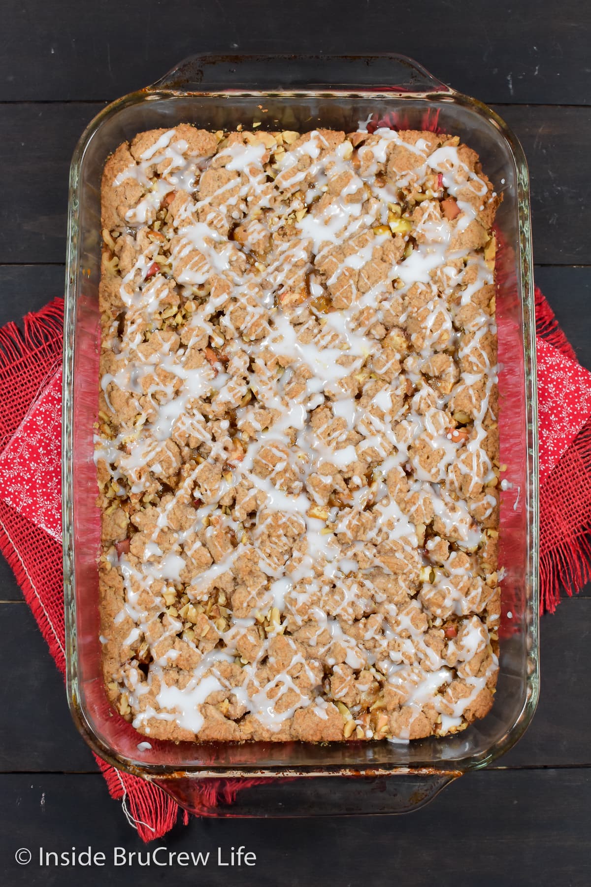 A glass pan with baked apple bars drizzled with glaze.