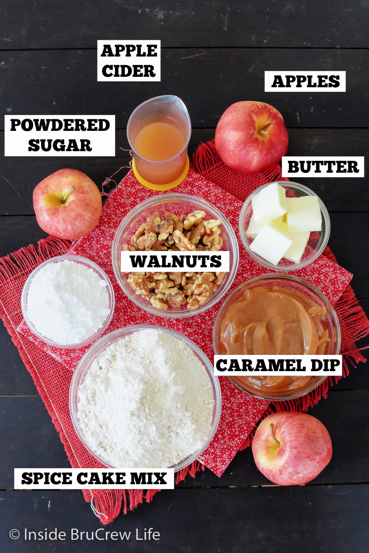 A brown board with bowls of ingredients needed to make apple bars.