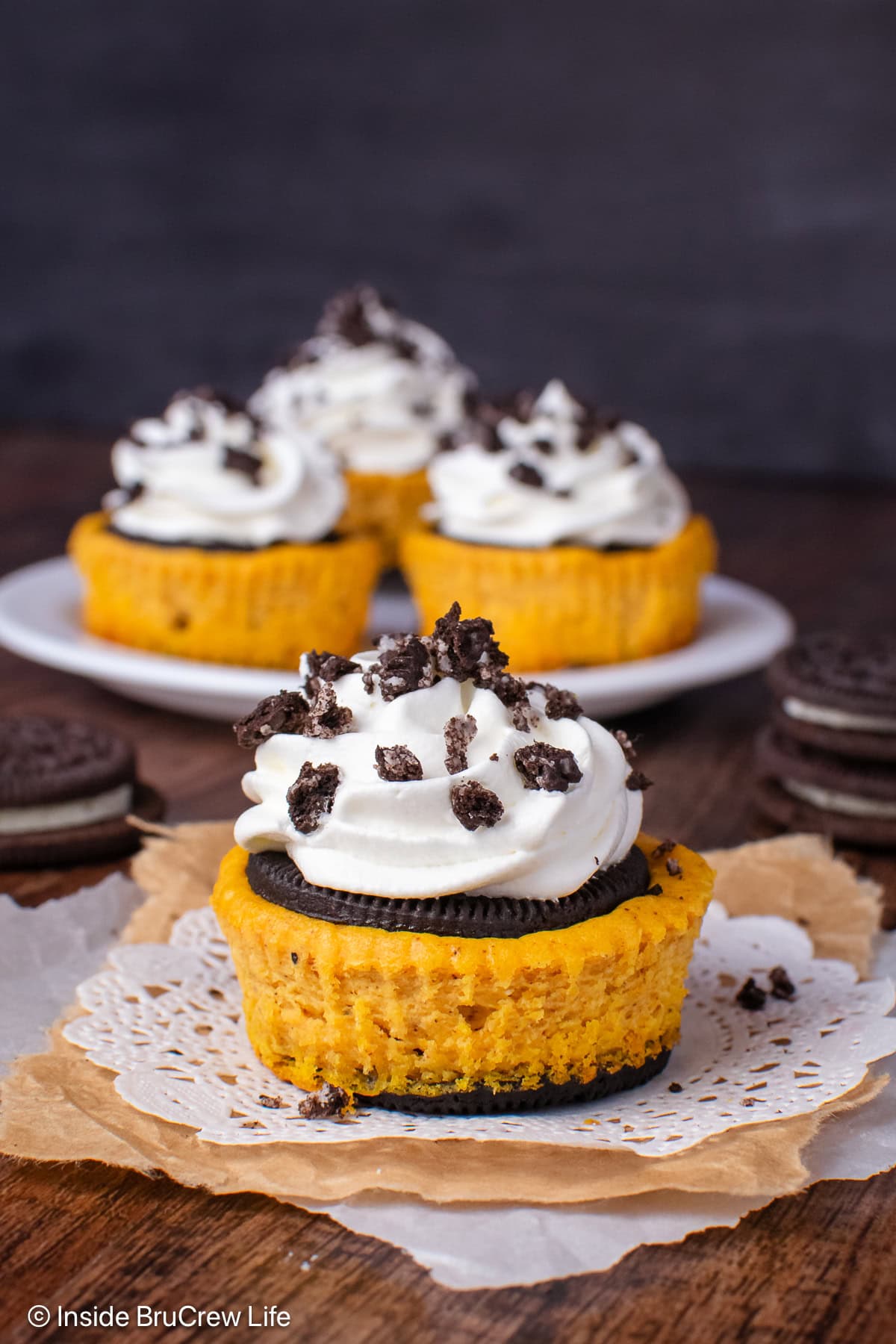 Mini pumpkin cheesecakes with Oreo crust on a white plate.