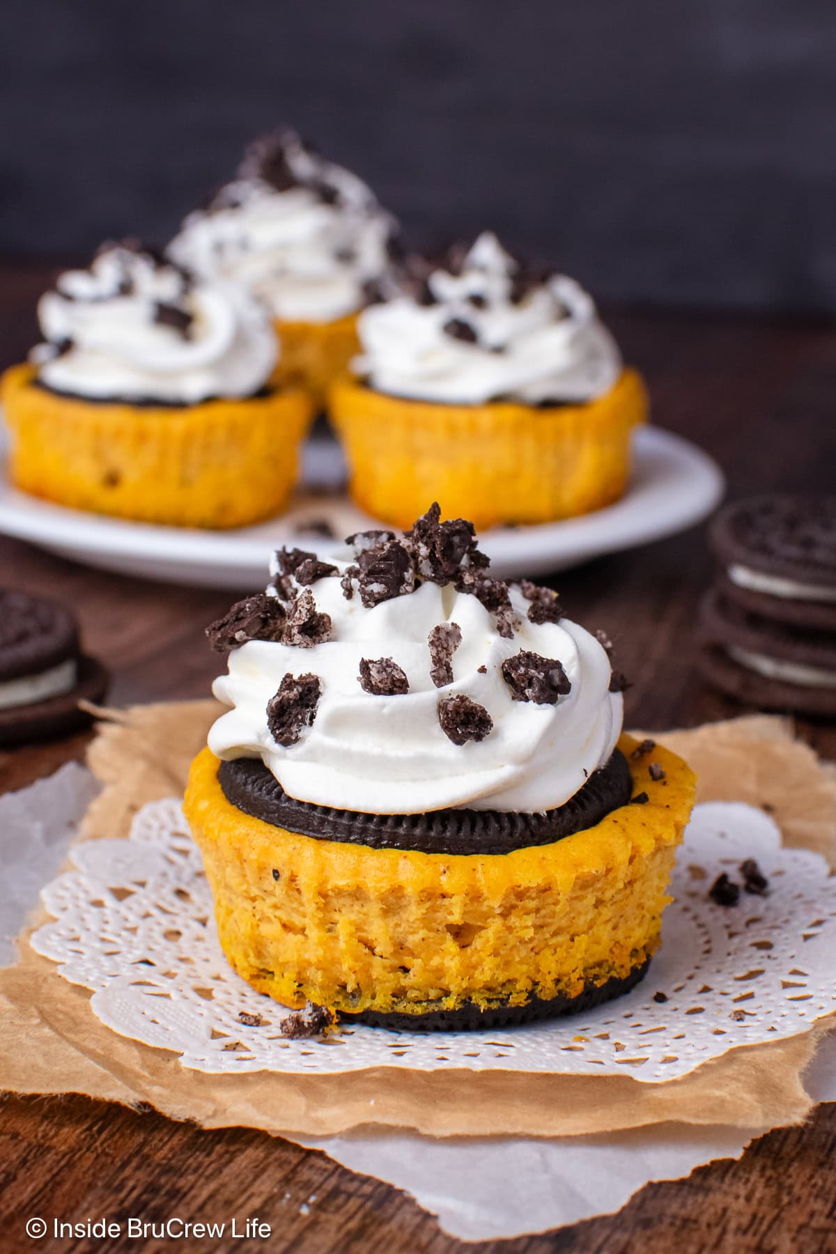 A pumpkin cheesecake bite topped with an Oreo cookie and whipped cream.