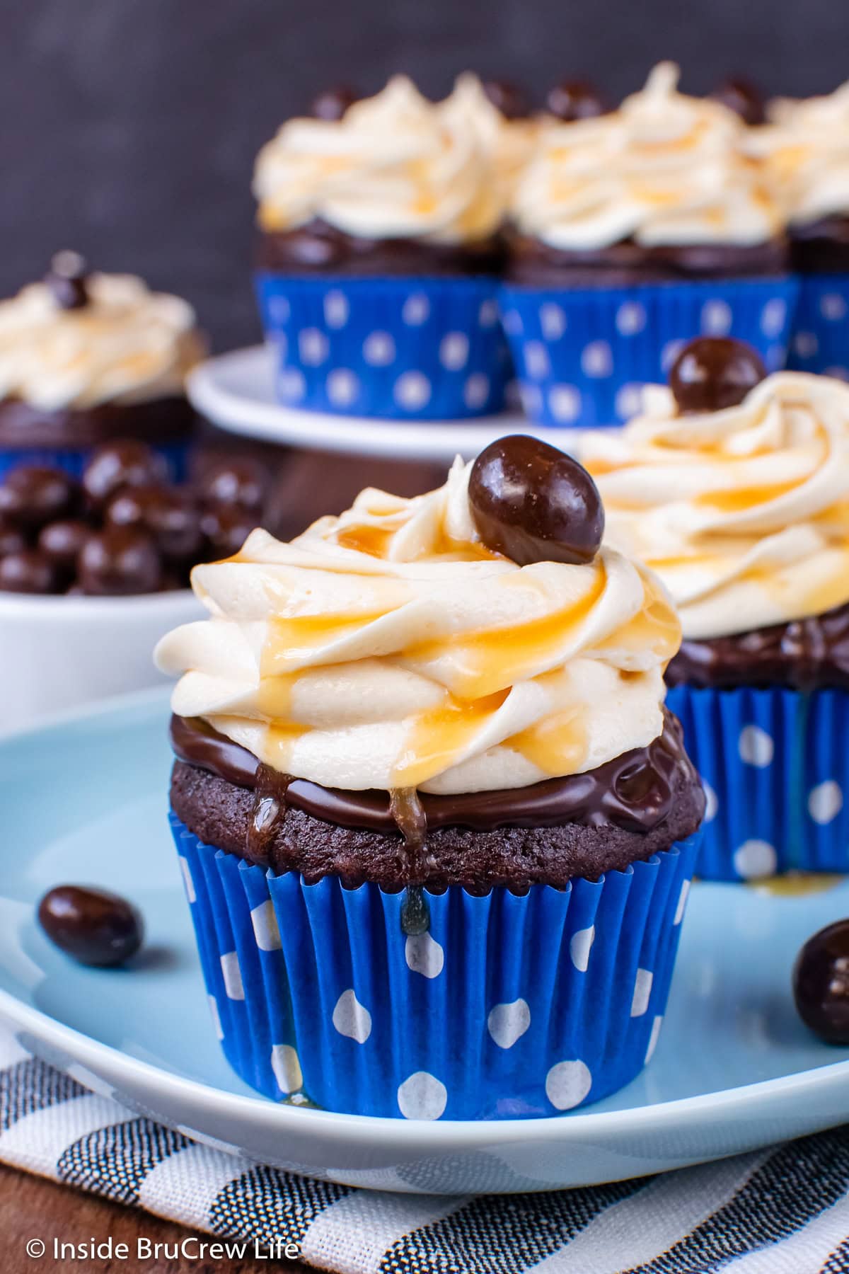 A chocolate cupcake topped with salted caramel frosting on a blue plate.