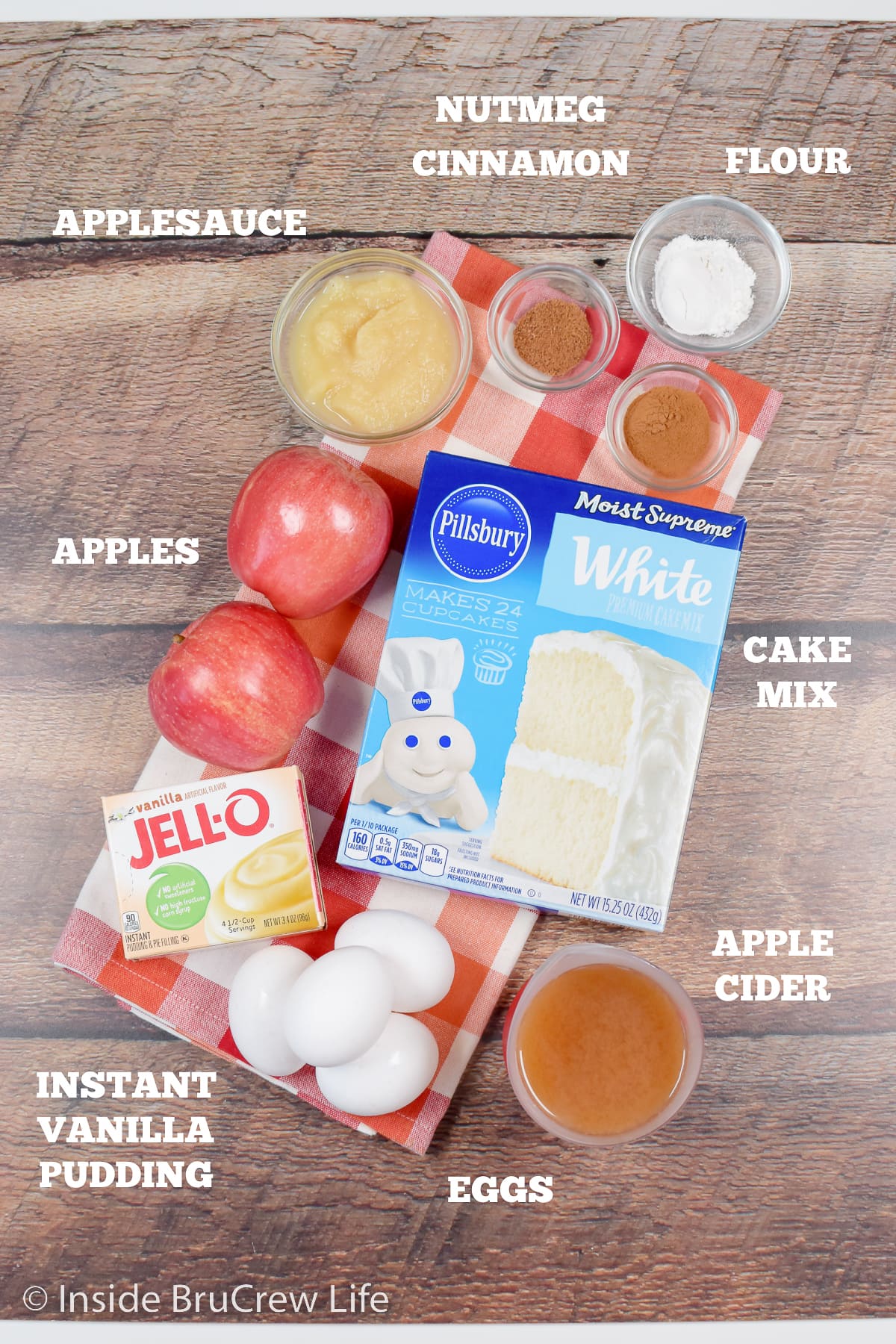 Bowls of ingredients needed to make an apple cake from a cake mix on a brown board.