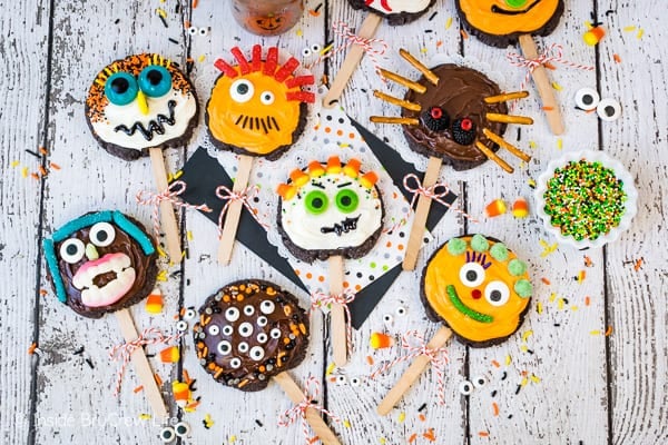 A white board with chocolate cookie pops decorated like monsters on it.