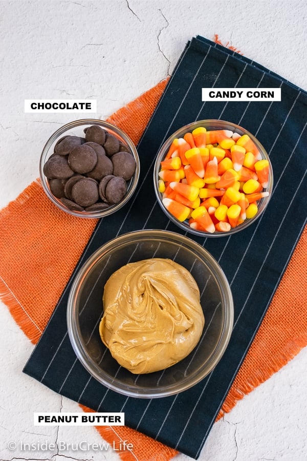 A white board with bowls of peanut butter, candy corn, and chocolate on it.