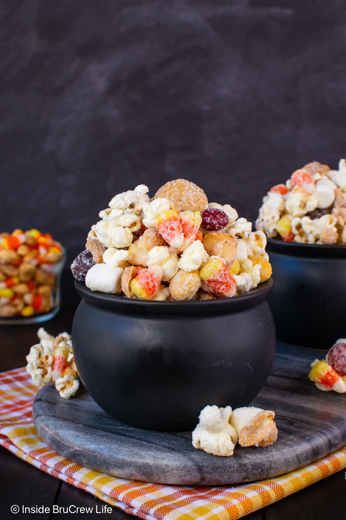 Black bowls filled with chocolate covered popcorn with candy corn.