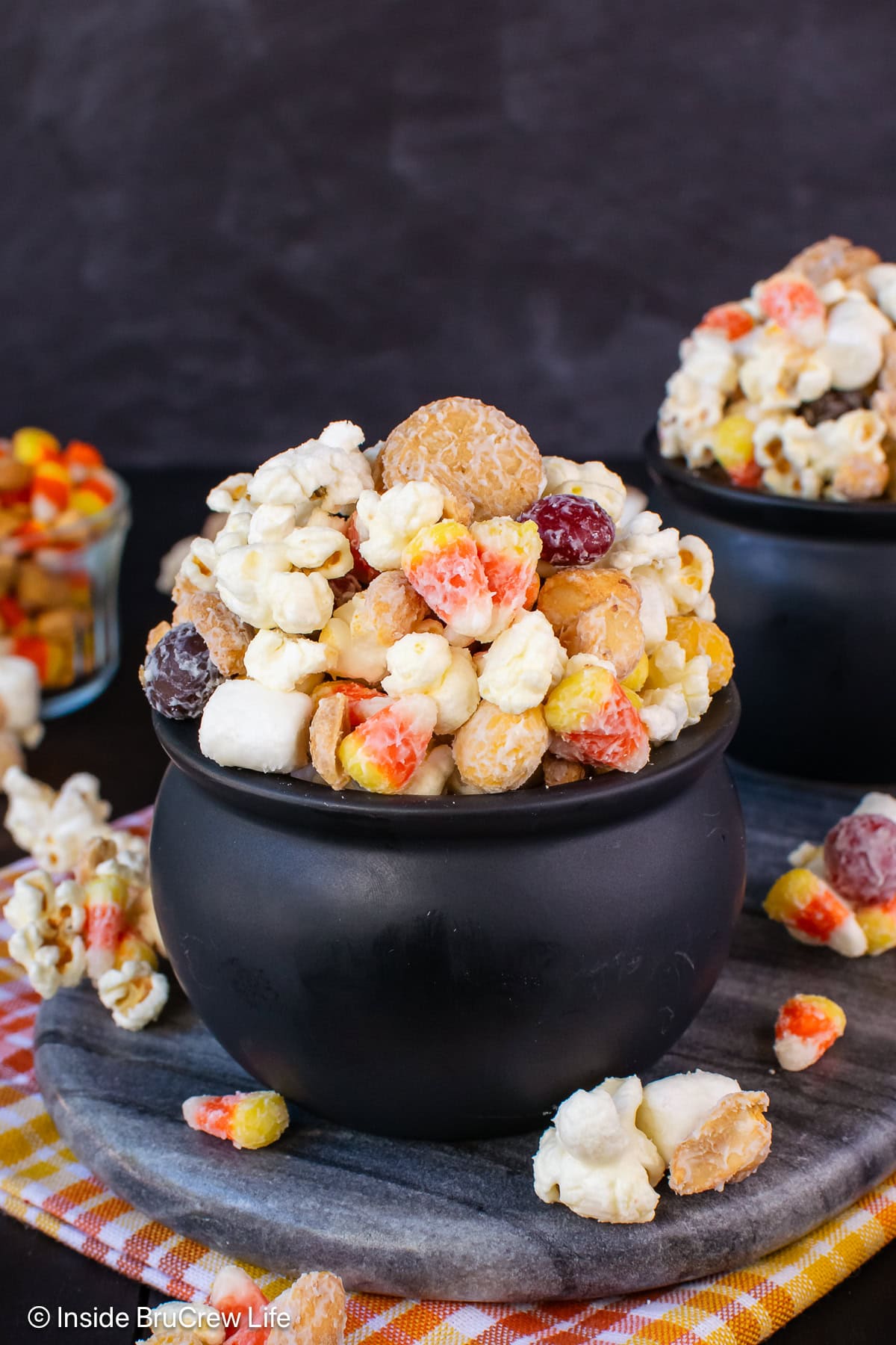 Bowls of candy corn popcorn on a gray tray.