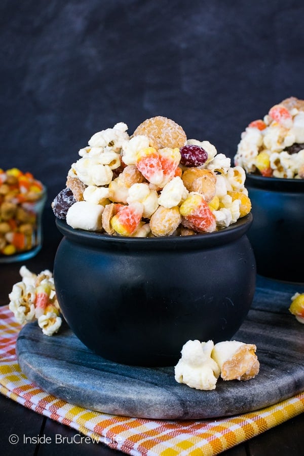 A black bowl on a slate tray filled with candy corn popcorn.