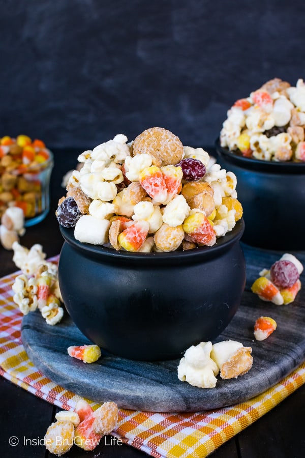 A black bowl overflowing with candy corn popcorn.