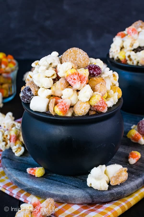 A black bowl filled with a white chocolate candy corn popcorn mix.