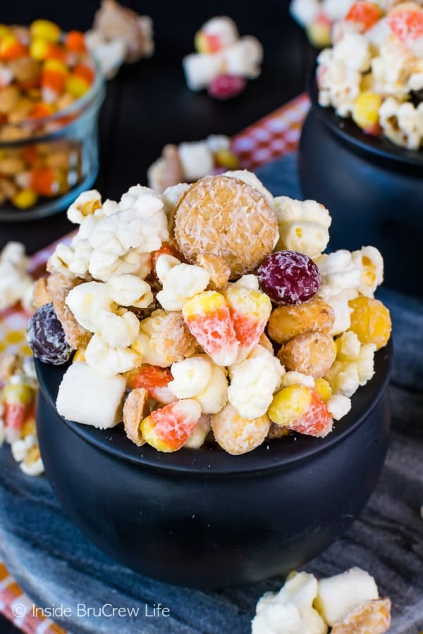 Close up picture of candy corn popcorn in a black bowl.