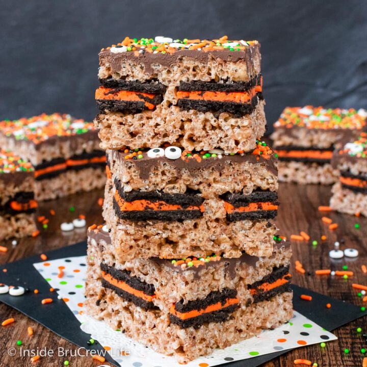 Three rice krispie treats with Oreos in them stacked on a napkin.
