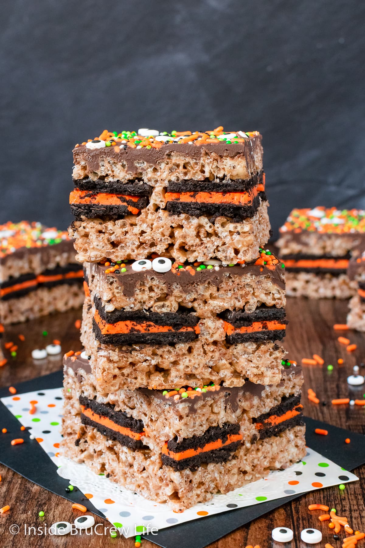 Three rice krispie treats with Oreos in them stacked on a napkin.