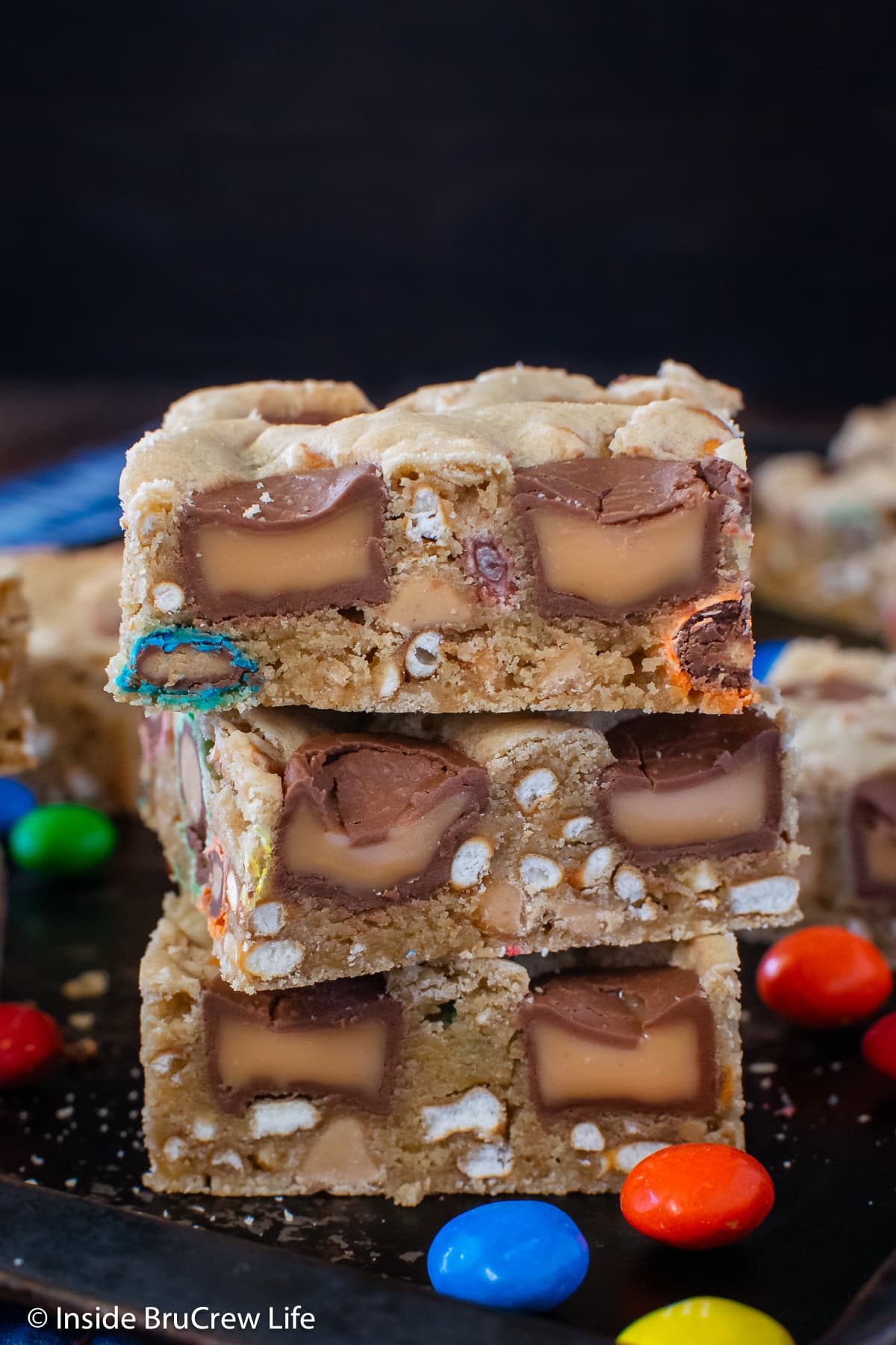 Three cookie bars stacked on a black pan.