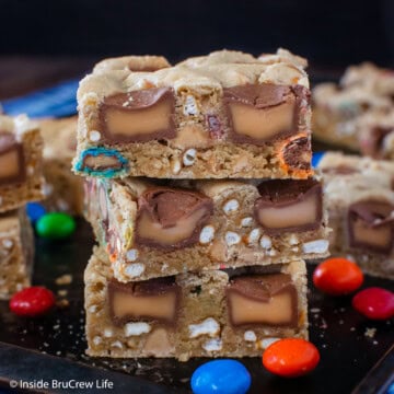Three cookie bars filled with candy stacked on a pan.