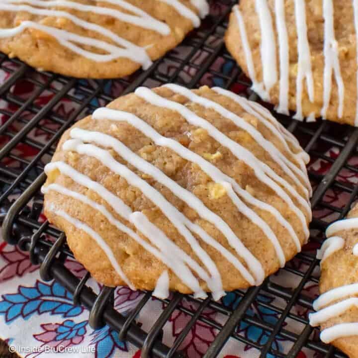 Toffee apple cookies with white chocolate drizzles on a wire rack.
