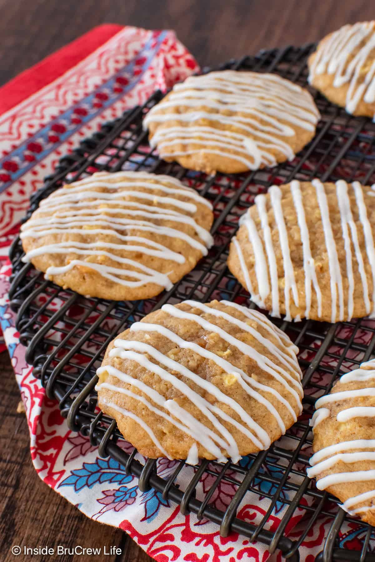 Toffee apple cookies with white chocolate drizzles on a wire rack.