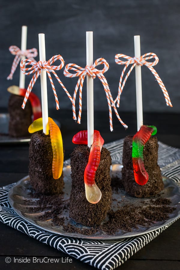 Dirt Marshmallow Pops - add a gummy worm to these chocolate covered marshmallows for a fun and easy dirt dessert. Make this recipe for Halloween or school parties! #halloween #dirtdessert #marshmallowpops #chocolatecoveredmarshmallows #gummyworms #halloween #nobakedessert #chocolate #marshmallows
