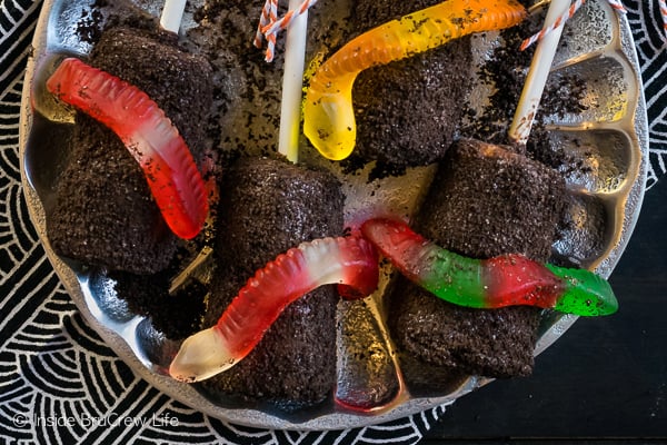 Dirt Marshmallow Pops - chocolate covered marshmallows covered with cookie crumbs and gummy worms makes a fun no bake dirt dessert! Perfect for school or Halloween parties! #halloween #dirtdessert #marshmallowpops #chocolatecoveredmarshmallows #gummyworms #halloween #nobakedessert #chocolate #marshmallows