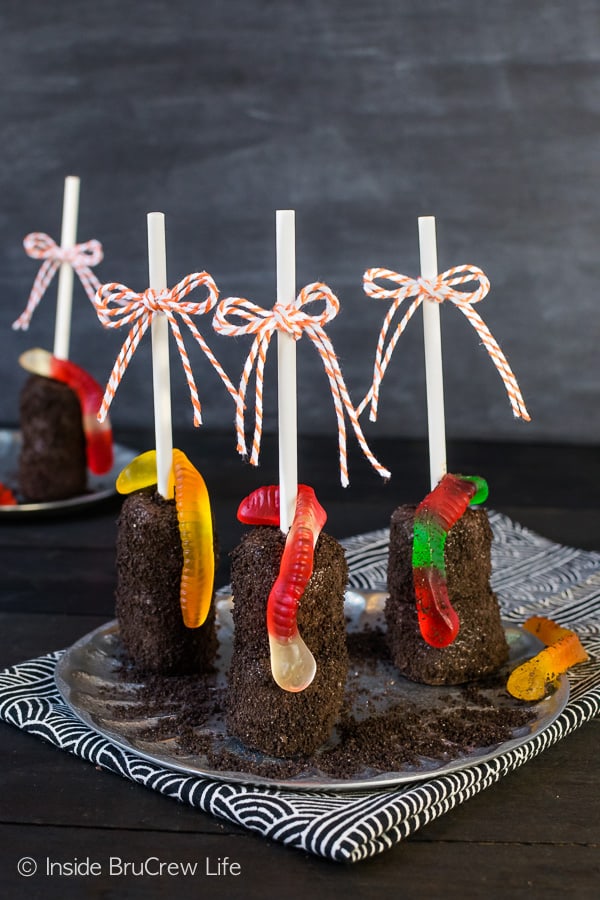 Dirt Marshmallow Pops - Oreo cookie crumbs and gummy worms transform chocolate covered marshmallows into a fun dirt dessert. Make this easy no bake recipe for Halloween parties! #halloween #dirtdessert #marshmallowpops #chocolatecoveredmarshmallows #gummyworms #halloween #nobakedessert #chocolate #marshmallows
